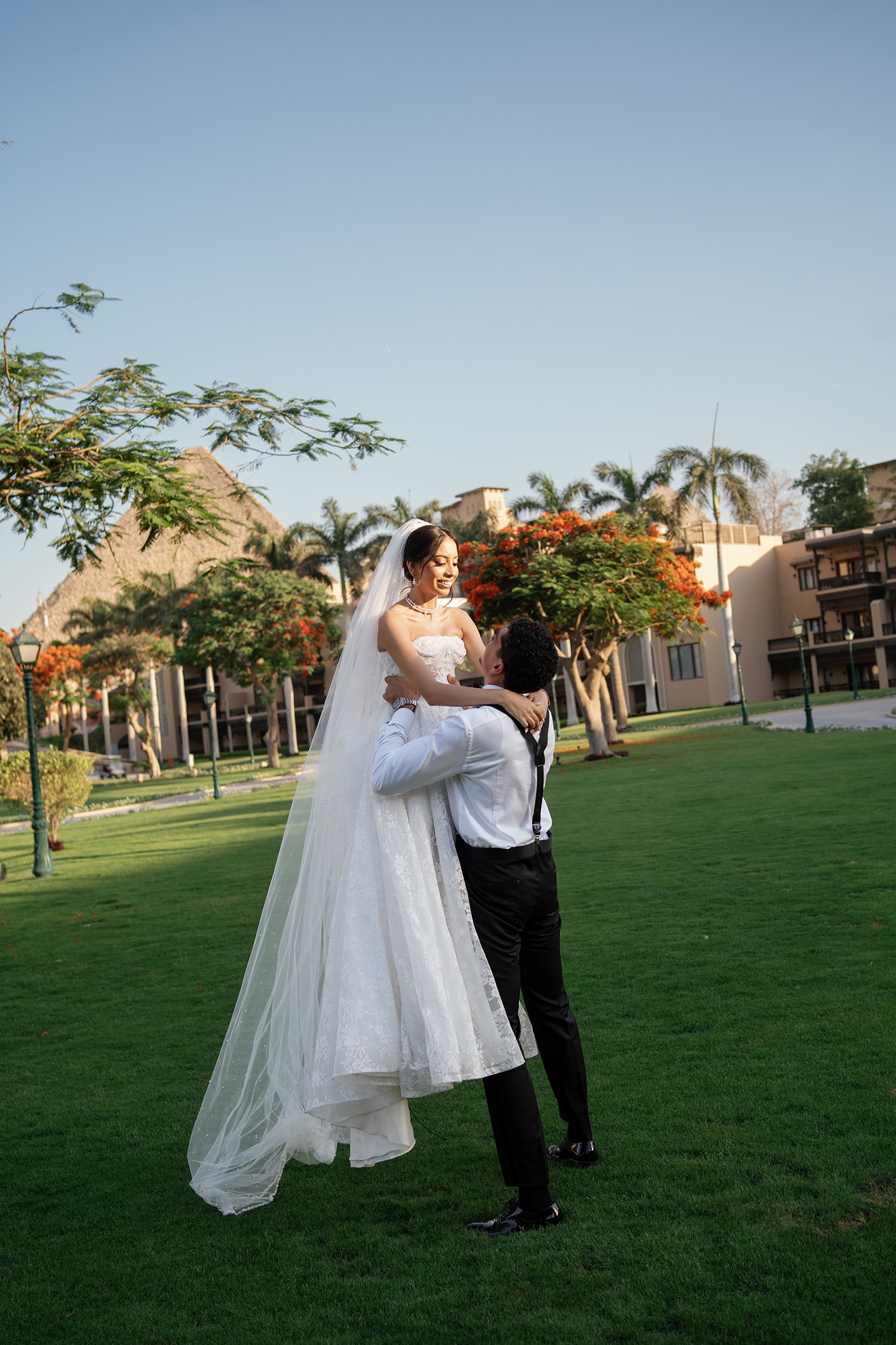 Groom carrying bride on grass lawn