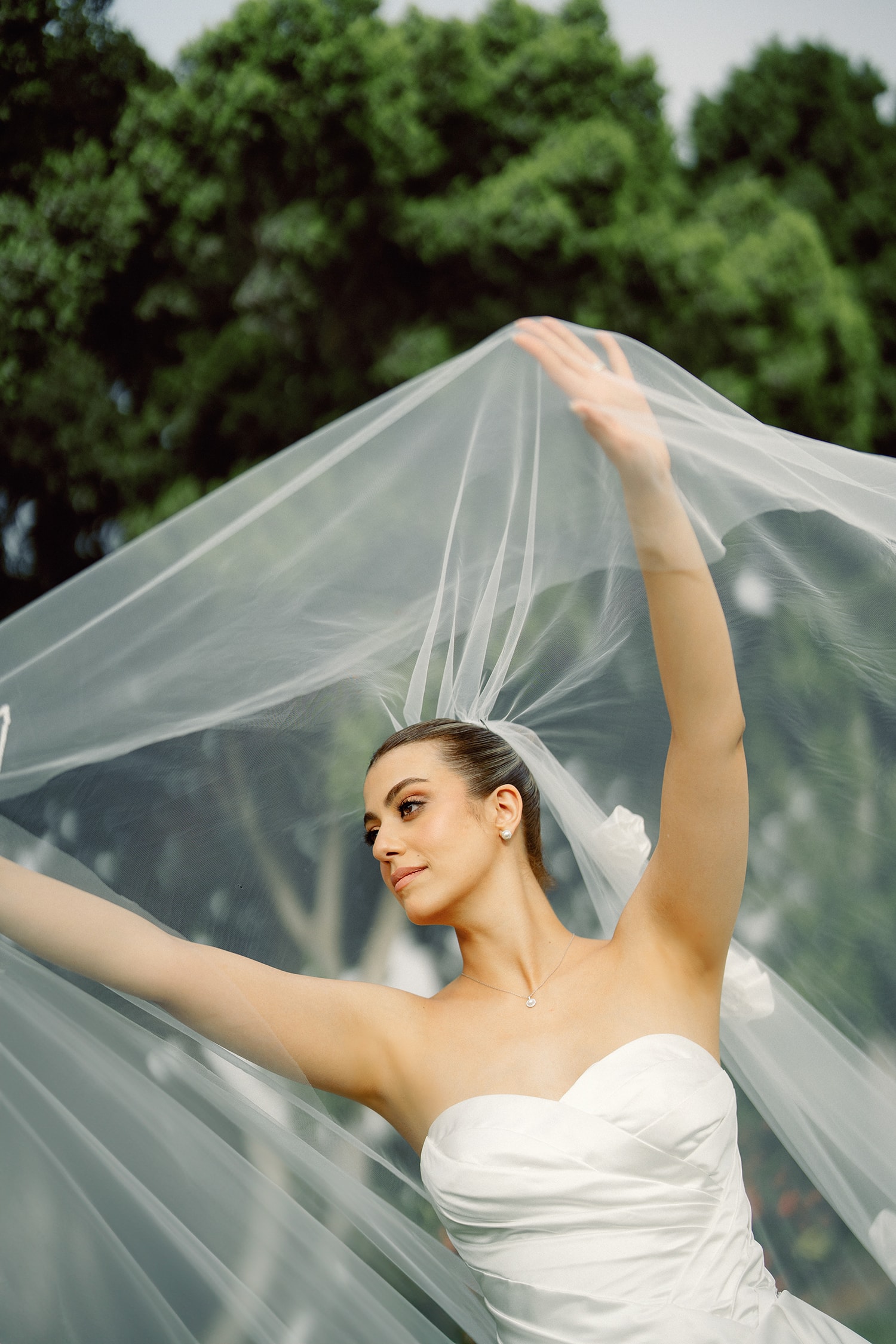 Bride in white dress flowing veil outdoors