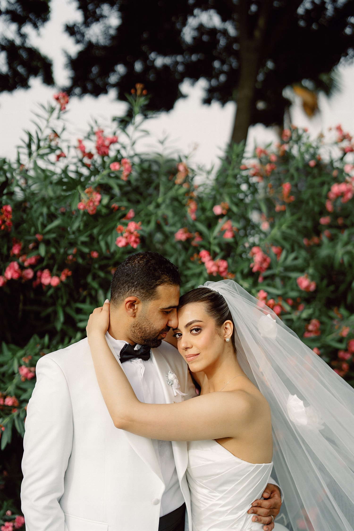 Bride groom embracing red flower garden