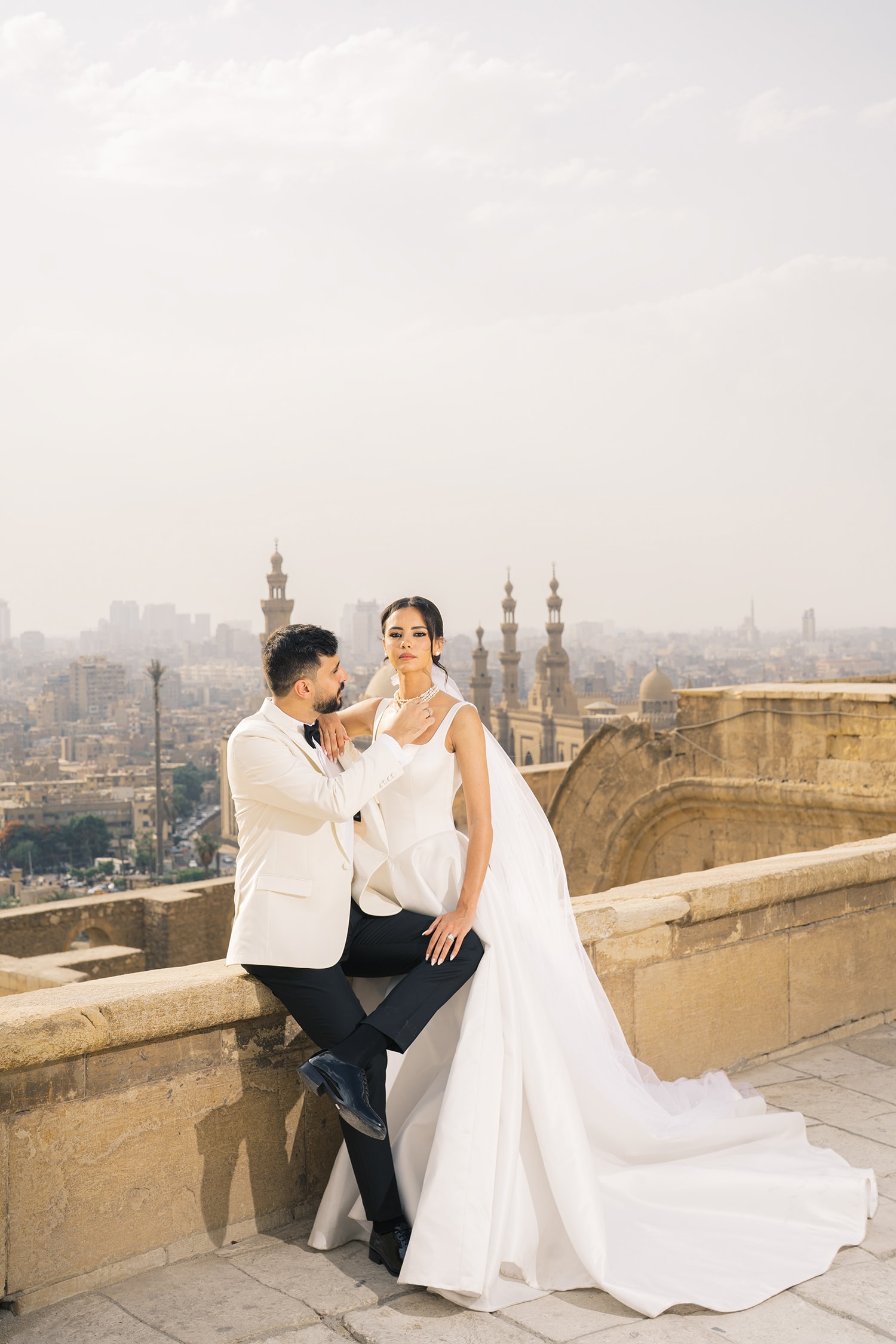 Couple in white wedding attire Cairo skyline