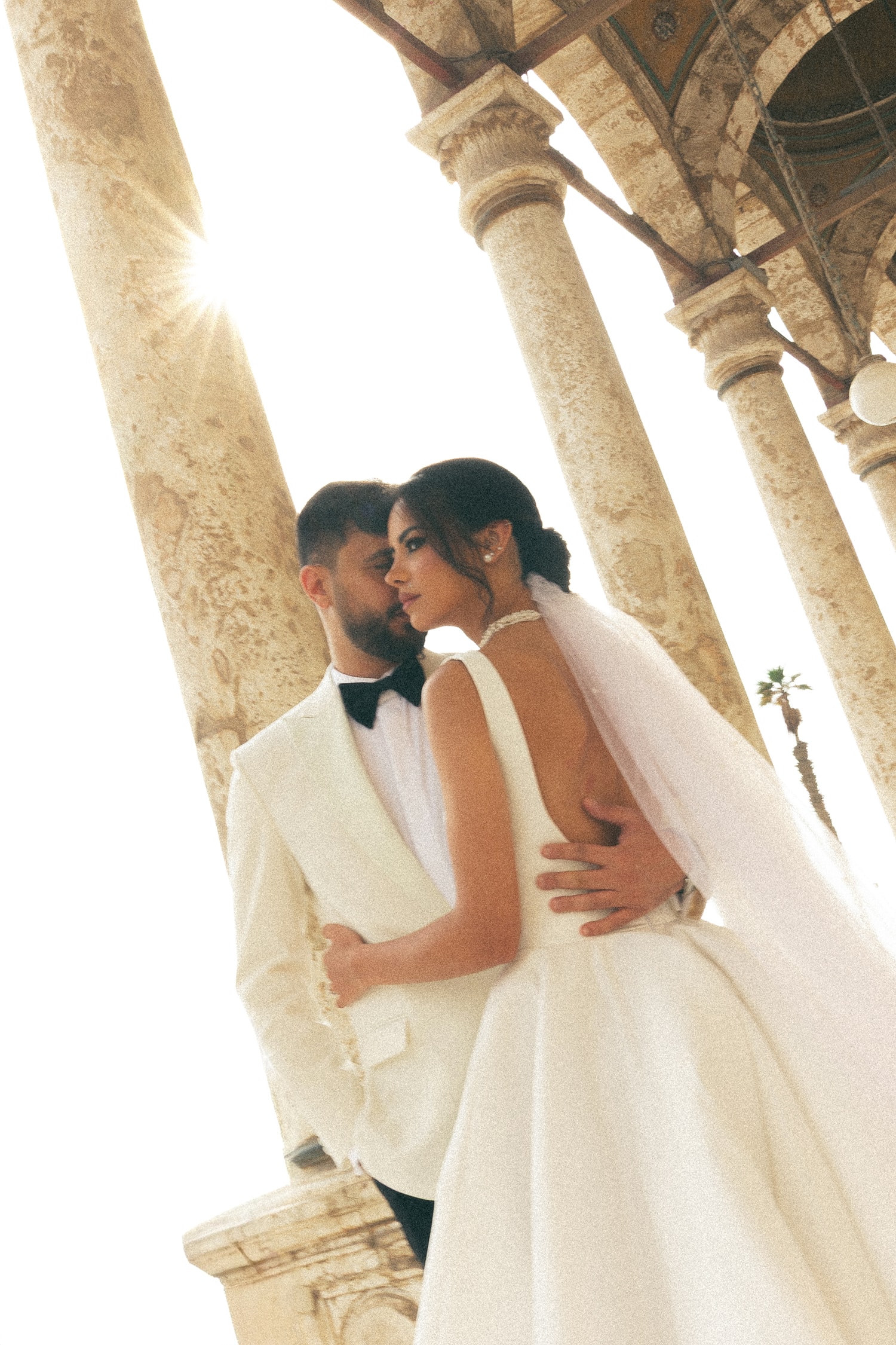 Bride groom embracing ancient stone columns