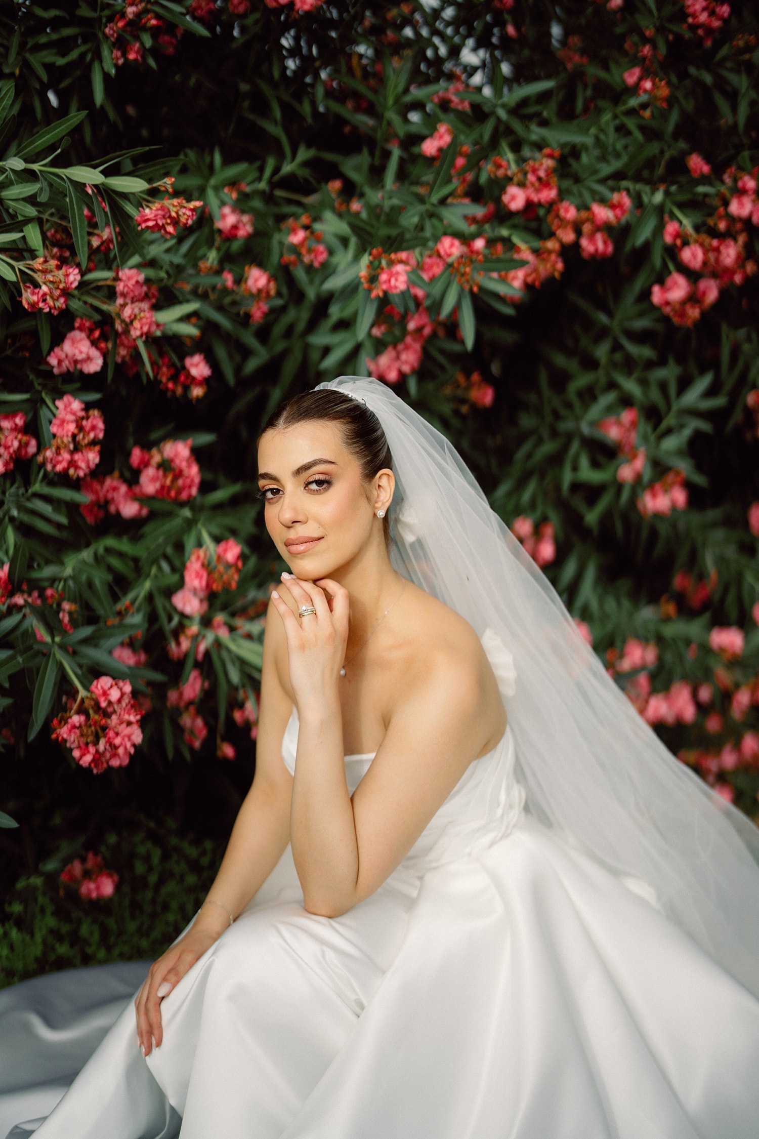 Bride posing against red flower backdrop
